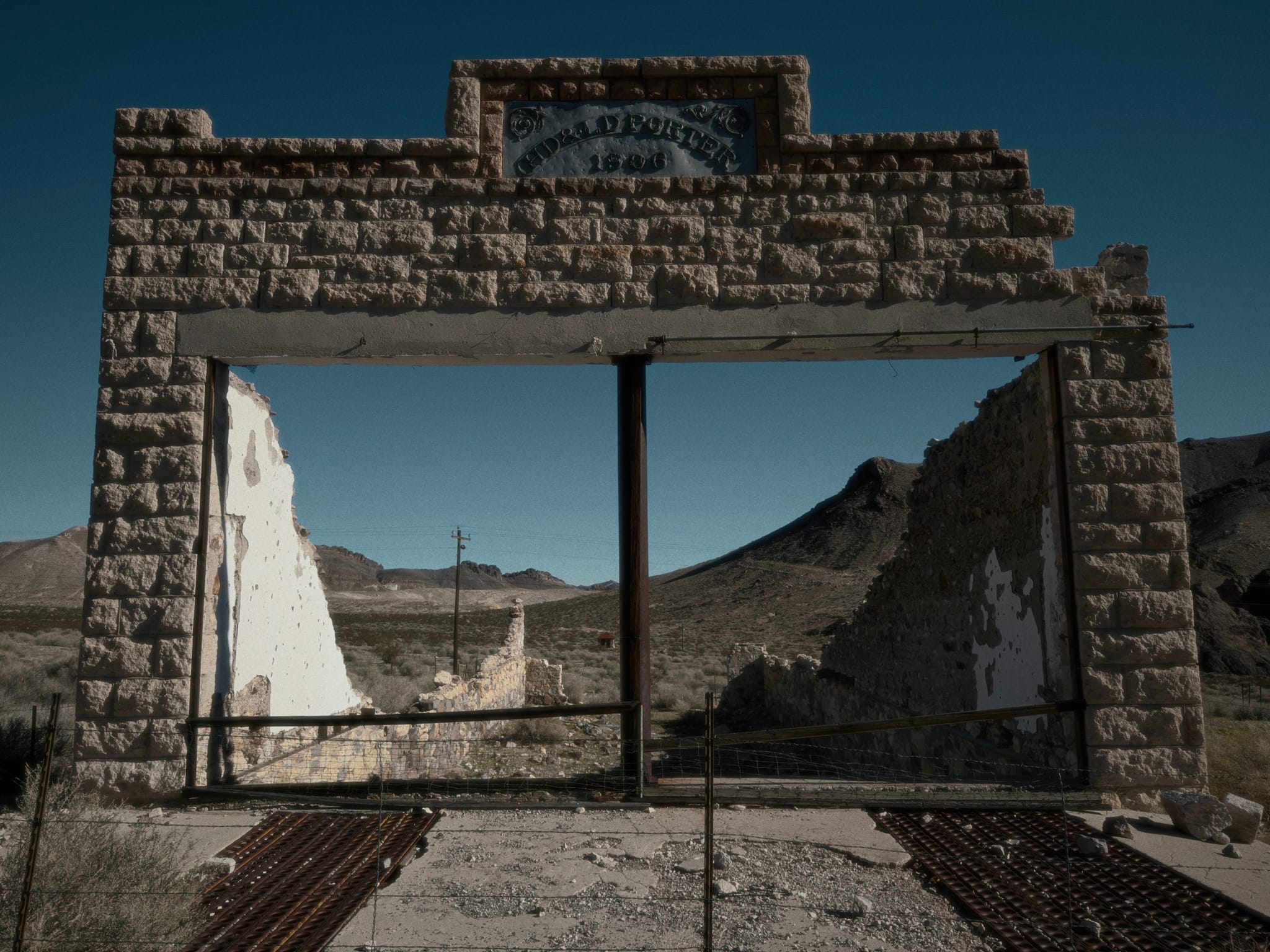 Stone doorway ruins with a wooden crossbeam in an abandoned desert settlement under a dark blue sky